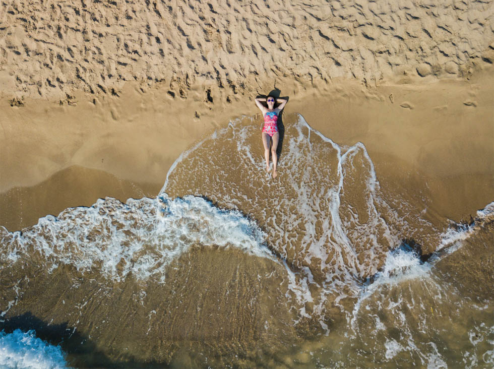 In the surf, shot from overhead drone, lady on a beach