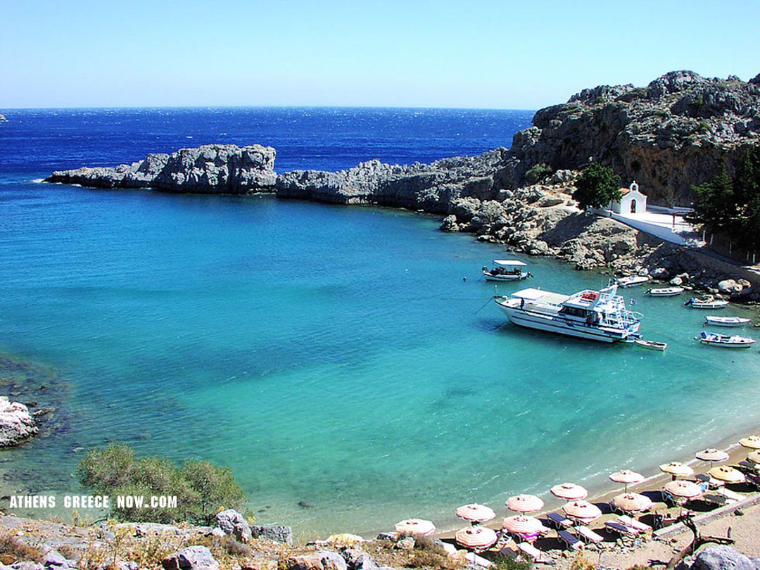 Rhodes Beach front with small church building and tourist boat